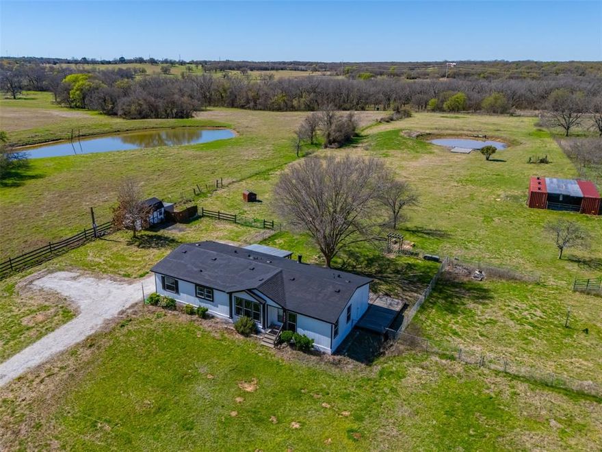 Tucked away on over 13 beautiful acres in Whitney, Texas, this fully updated 3 bedroom, 2 bathroom modular home offers 1,680 square feet of comfortable living space surrounded by peaceful country scenery. Renovated in 2022, the home features modern finishes, an open concept layout, and spacious living and dining areas designed for both everyday living and entertaining. Large windows provide abundant natural light and showcase scenic views of the property’s mix of open grazing land and mature wooded areas. The outdoor improvements completed in 2024 transform this property into a true private retreat. Enjoy your fishing pond filled complete with a new deck and floating dock perfect for relaxing, fishing, or entertaining. The property also features new front and back fencing, offering both security and functionality for livestock, pets, or privacy. Additional improvements include a storage shed and two shipping containers connected by a covered parking area. One container has been thoughtfully converted into a dedicated exercise room, while the other provides excellent equipment and tool storage, offering flexibility for hobbies, fitness, or workspace needs. With a blend of open pasture and wooded acreage, this property provides endless opportunities for recreation, gardening, livestock, or simply enjoying the quiet Texas countryside. Located in Whitney, Texas near Lake Whitney and within convenient driving distance of the Dallas Fort Worth area, this property is ideal as a full time residence, weekend getaway, or private retreat. Rare opportunity to own versatile acreage with move in ready improvements, scenic views, and exceptional outdoor amenities.
