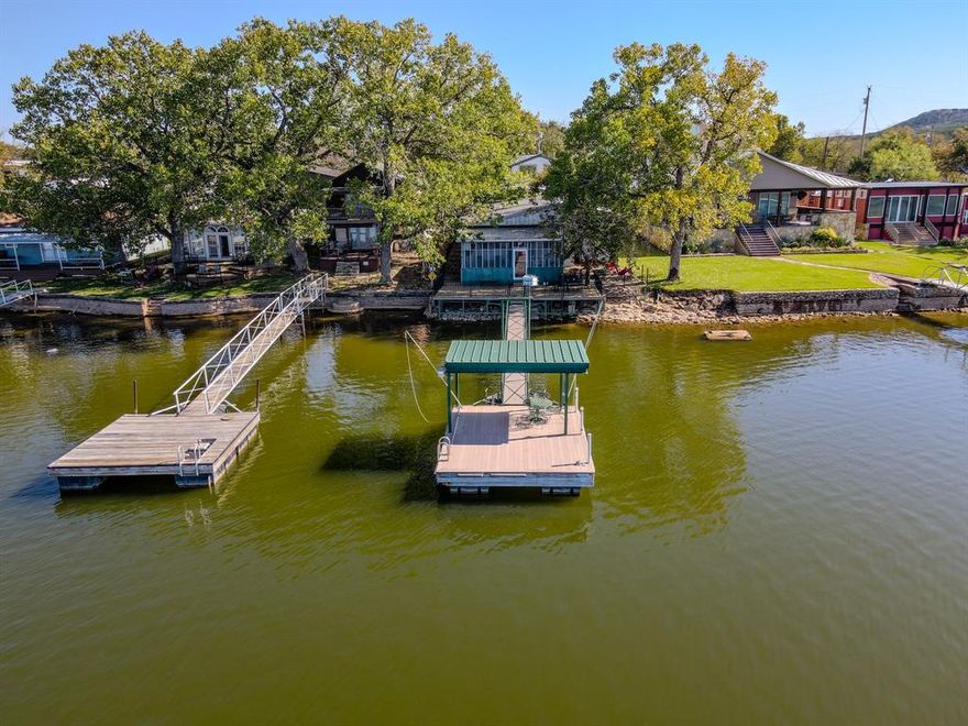 Charming waterfront cabin perfectly positioned on a quiet cove of Possum Kingdom Lake. Enjoy lake life to the fullest with a spacious screened in porch, waterside patio, and cozy fire pit overlooking breathtaking sunsets. The property features a 55x20 foot climate controlled shop with two bedrooms and a full bathroom, offering comfortable guest accommodations or space to store all your lake toys. The main cabin provides a warm and inviting living space with classic PK character, while the covered Cantina creates the ultimate outdoor entertaining area for family and friends. This well maintained retreat includes a fenced yard and private dock with low maintenance Trex decking, all set in a quiet neighborhood on the popular peninsula. A rare find combining charm, comfort, and functionality right on the water.
