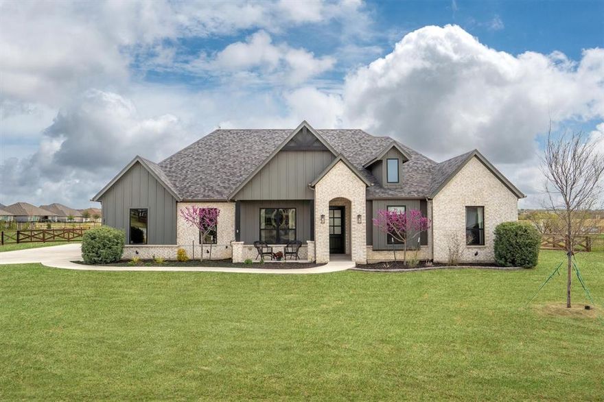 Tucked away on a full acre in Stardust Ranch, this single-story 4 bed, 3 bath home offers a rare blend of space, flexibility, and thoughtful design, highlighted by a true multi-generational suite that’s increasingly hard to find. Designed for independence and privacy, this fully equipped suite features its own kitchen, living area, bedroom, full bath, and stackable washer and dryer, along with separate access to both the driveway and backyard. At the heart of the home, the kitchen and living spaces come together in a way that feels both elevated and inviting. Custom cabinetry is paired with quartz countertops, a statement wood vent hood, patterned tile backsplash, and an oversized island that anchors the space. The living room makes a lasting impression with vaulted ceilings, exposed wood beams, built-in cabinetry, and a floor-to-ceiling stone fireplace - creating a warm and comfortable setting for everyday living or entertaining. The primary suite offers a true retreat with a tray ceiling, abundant natural light, and a spa-inspired bath featuring dual vanities, a freestanding soaking tub, and an oversized walk-in shower with bench seating. The single-story layout also offers wheelchair accessibility, making the home as functional as it is beautiful. Step outside to your private backyard retreat complete with a pool and spa, expansive patio, and plenty of room to play, garden, or simply enjoy the wide-open space of your acre lot. Automatic patio screens create a comfortable outdoor living experience year-round, while a storage shed adds additional functionality. Solar panels provide energy efficiency and long-term savings.Located in Northwest ISD and just minutes from the future HEB and upcoming commercial development, this home offers the best of quiet country living with exciting growth nearby.