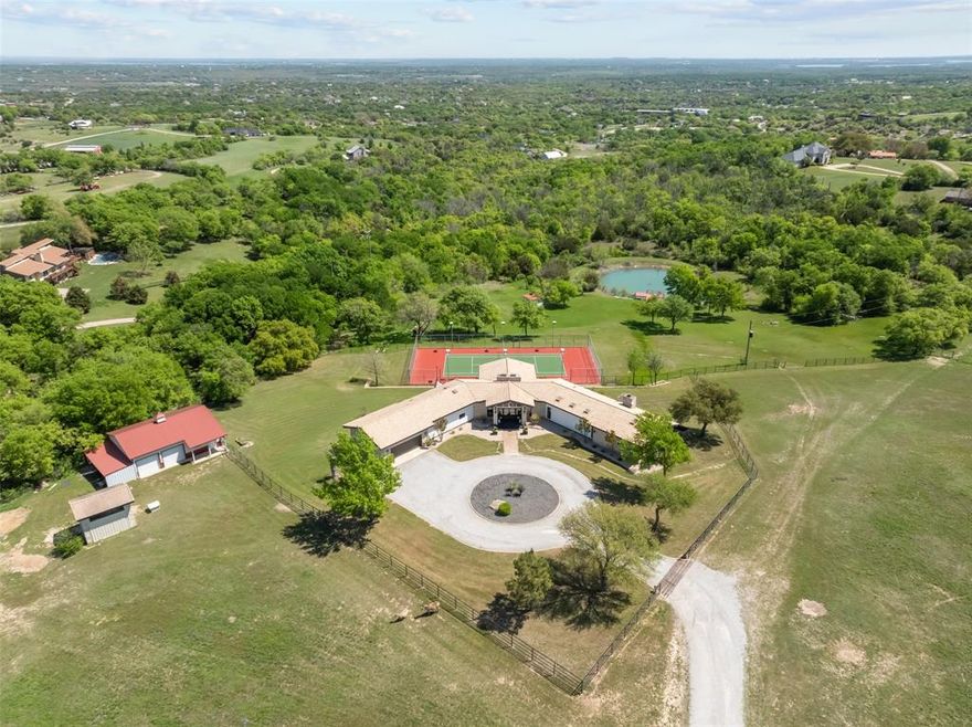 Nestled on nearly 13 pristine acres in acclaimed Aledo ISD, this newly remodeled 4-bedroom, 4-bathroom contemporary retreat blends modern elegance with Texas charm. A dramatic grand entry welcomes you into an open-concept living space featuring a stunning floor-to-ceiling stone fireplace and walls of windows framing scenic countryside views. The gourmet kitchen is an entertainer’s dream—boasting sleek black cabinetry, a designer wood range hood, Thermador appliances, a wine closet, and a spacious butler’s pantry.

The versatile layout offers a lower level suite with private living area, full bath, bedroom, and sauna that opens to the expansive lower deck. The luxurious primary suite includes a fully renovated spa-like bathroom and sitting area to enjoy morning coffee with a sunrise view. Additional main-level highlights include a home office with custom finishes, a guest bedroom, and two more beautifully appointed bathrooms.

Step outside to take in the lushly landscaped grounds with a serene pond and fishing dock, cross-fenced pastures with loafing shed and shop, and ample room to run horses or expand with more homes. Entertain from the newly refinished tennis court or host gatherings on the multi-tiered deck overlooking the property. This Texas farmhouse-inspired dream home delivers privacy, space, and refined living in a premier location.

Room to expand for the perfect multiple family homesite or maintain your peace and privacy with your own personal Texas retreat.