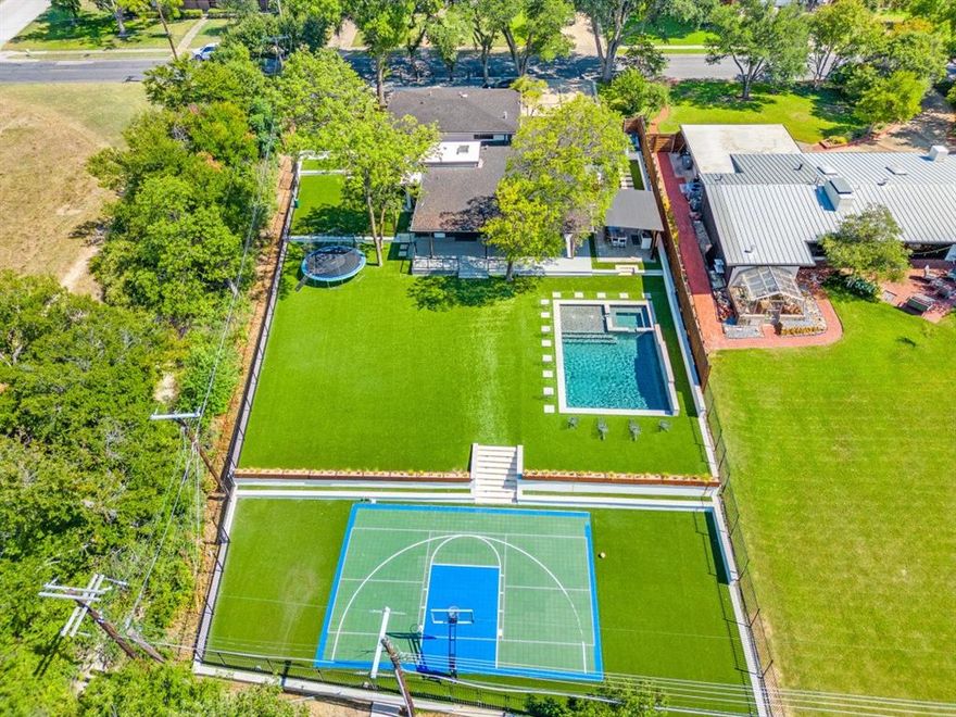 A Rare Mid-Century Modern Estate in Dallas was built in 1955 by Trammell Crow as a home for his mother, this home has been restored and expanded (2022–2024) to blend architectural heritage with modern function. Over half an acre, one of the highest elevations in Dallas and bordered by Norbuck Park, property offers privacy and natural views rarely found within city limits. Glass walls and sliding doors brighten the home and link it to the outdoors.  four bdrms and three bath, designed for functionality. The chef’s kitchen features built-in refrigeration, double gas ovens, gas cooktop, oversized granite island deep double sink, custom seating, and extensive cabinetry. A formal dining room opens to the main living area. A flexible secondary living space. A private bedroom w full bath on main floor. Upstairs, two more bedrooms, full bath, and the primary suite—with soaking tub, walk-in shower,double vanity, custom cabinetry. Warm wood flooring pairs with stone,marble,and tile throughout for a prestine feel.Outdoor Paradise Designed for personal enjoyment and large-scale entertaining, the backyard includes a sparkling pool and spa, full-size sport court, and generous sun deck, surrounded by professional low-maintenance landscaping with artificial turf. A broad covered deck overlooks Norbuck Park and leads to an outdoor kitchen equipped with dual refrigerators, gas grill, cooktop, beverage fridge, and granite bar. An enclosed dog run with pet doors enhances convenience for pet owners. Distinctive Features, Sweeping curved driveway & attached garage, Whole-home Generac emergency power system; Oversized laundry room with stone and tile finishes, Careful preservation of original architectural details paired with modern updates.This home represents the best of Dallas living: architectural significance, stylish updates, and a park-like setting that feels both private and serene—ideal for hosting or simply enjoying quiet moments surrounded by nature.