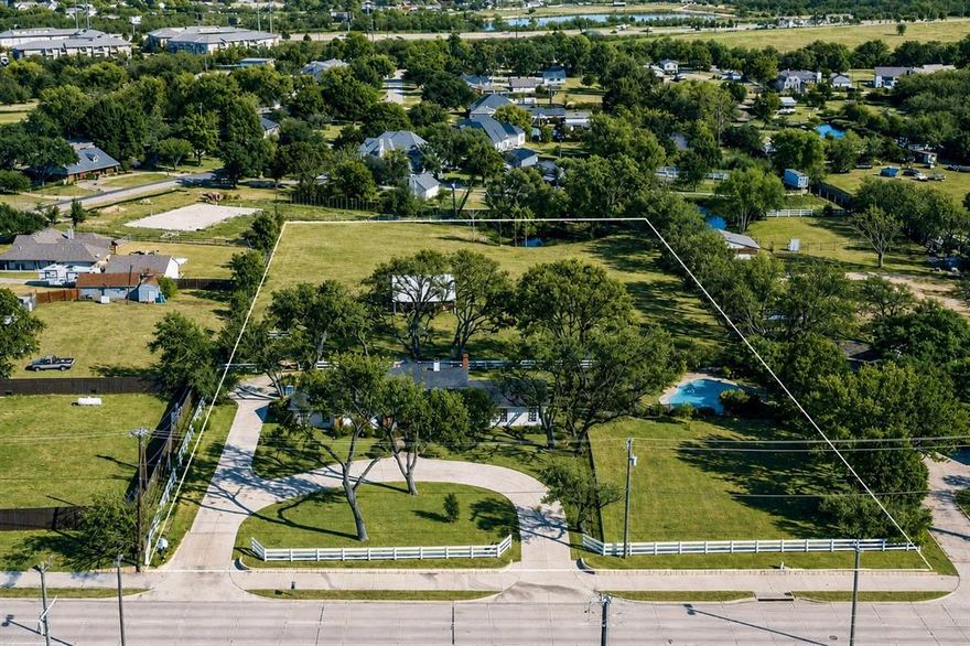 Set on 2.83 private acres in Rowlett, this one-of-a-kind property is the rare blend of space, flexibility, and city convenience—perfect for buyers who want room to grow, spread out, and not worry with HOAs. The layout supports multi-generational living, plus outdoor infrastructure ideal for a workshop setup, equipment storage, hobby space, or future personalization (buyer to verify city requirements etc).
Outdoor amenities deliver true “staycation” living: a fenced gunite in-ground pool with water feature, mature trees, sprinkler system, cross-fencing, and a pond toward the back—ideal for recreation, gardening, or simply enjoying the peace and privacy of acreage. The property also includes a substantial barn-stable building with functional work areas and water access, making it equally useful as flex space for projects, storage, or hobby needs (horses and certain livestock permitted if desired).
The home is full of one-of-a-kind character, blending timeless details with a warm, country-comfort feel you just don’t get in cookie-cutter builds.  3 bedrooms, 4 baths (3 full + 1 half) with an exceptionally livable flow: two living areas and two dining areas, study with builtins, oversized rooms, and great storage throughout. Updates and character shine through with hardwood flooring,  granite counters, built-ins, wainscoting, and abundant natural light. The primary ensuite is show-stopping updated top to bottom with a soaking claw-foot tub and a two-sided fireplace shared between the bedroom and the bath and high-end finishes throughout, truly remodeled to the nines. The floorplan lends itself beautifully to extended-family living with a second primary suite option and an in-law-style arrangement, plus a spacious wet bar area for entertaining. Two fireplaces add warmth and personality. A rare Dallas County acreage opportunity with the freedom to make it your own. The location is ideal with easy access to PGBT 190 to get you where you need to go with ease.