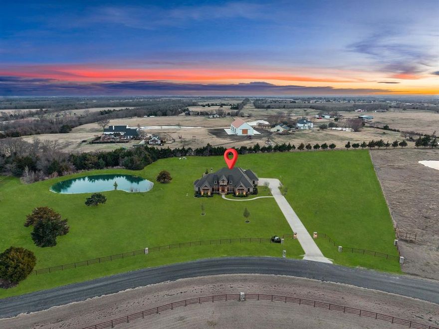 This rare 6+ acre property in Celina with NO HOA, agricultural exemption with a low tax rate supported by an established beekeeping farm,, private pond, and saltwater pool offers breathtaking sunset views and the freedom of country living in one of North Texas’ fastest-growing areas. Located in the sought-after Celina ISD, it offers peaceful country living while remaining conveniently close to the area’s growing amenities and conveniences. Built by Schramme Custom Homes, this 1.5-story home features the majority of its square footage on the main level, with only a spacious game room upstairs. Inside, the home features architectural details including brick accent arches and custom built-ins, along with a stunning stone fireplace accented with exposed wood beams. The gourmet kitchen showcases Taj Mahal countertops and backsplash, underlit cabinetry, spot-free gold faucets, a granite sink, and reverse osmosis drinking water. The entire home, including the cabinetry, has been freshly painted, and new hardwood floors flow throughout the first floor. The primary suite offers a spa-inspired bathroom with a soaking tub, separate shower, and dual vanities, while each bedroom connects to a bathroom, providing comfort and privacy. A flexible bonus room can serve as a playroom or home gym and a private study with built-ins provides an ideal work-from-home space. Upstairs, the game room features brand-new carpet and a wet bar, perfect for entertaining. Step outside to enjoy the extended covered patio with a built-in grill overlooking the saltwater pool and private stocked pond, creating the perfect setting for relaxing evenings or hosting gatherings. A convenient bathroom with patio access adds ease for poolside entertaining. Additional amenities include 50-amp RV hookups, upgraded electrical and AV systems, landscaping enhancements, and three refrigerators that convey. This property delivers the rare opportunity to enjoy acreage living with space and privacy.