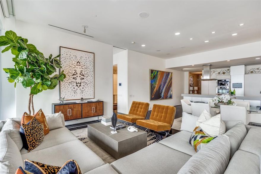 Step into this extraordinary 2-bedroom, 2.5-bath residence with study, ideally positioned on the coveted southwest corner and offering uninterrupted panoramic views of Downtown Dallas, the Arts District, Fair Park, theaters, museums, and Klyde Warren Park. A dramatic wall of 10-foot windows and 11-foot ceilings frame the skyline day and night, while a full-length 552-square-foot covered terrace with outdoor fireplace creates a stunning extension of the living space.
Designed for elevated entertaining, the residence features a Bulthaup kitchen with quartz countertops, Sub-Zero and Miele appliances, including a gas cooktop, built-in refrigerator, microwave, double beverage drawers, and wine refrigerator. The open-concept layout includes a dining area and two spacious living areas, all oriented toward the terrace and breathtaking city views.
The primary suite offers a serene retreat with a luxurious ensuite bath and a custom wood-designed closet tailored for optimal organization. The secondary bedroom features an ensuite bath, walk-in closet, and a full wall of custom storage. Museum-finished walls and granite and limestone flooring throughout complete this sophisticated urban residence.
The expansive terrace is outfitted with an outdoor kitchen, including grill, refrigerator, and storage—perfect for entertaining against the city skyline. Additional features include secure basement garage parking and a 50-square-foot climate-controlled storage room.