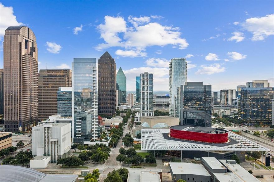 Step into this extraordinary 2-bedroom, 2.5-bath residence with study, ideally positioned on the coveted southwest corner and offering uninterrupted panoramic views of Downtown Dallas, the Arts District, Fair Park, theaters, museums, and Klyde Warren Park. A dramatic wall of 10-foot windows and 11-foot ceilings frame the skyline day and night, while a full-length 552-square-foot covered terrace with outdoor fireplace creates a stunning extension of the living space.
Designed for elevated entertaining, the residence features a Bulthaup kitchen with quartz countertops, Sub-Zero and Miele appliances, including a gas cooktop, built-in refrigerator, microwave, double beverage drawers, and wine refrigerator. The open-concept layout includes a dining area and two spacious living areas, all oriented toward the terrace and breathtaking city views.
The primary suite offers a serene retreat with a luxurious ensuite bath and a custom wood-designed closet tailored for optimal organization. The secondary bedroom features an ensuite bath, walk-in closet, and a full wall of custom storage. Museum-finished walls and granite and limestone flooring throughout complete this sophisticated urban residence.
The expansive terrace is outfitted with an outdoor kitchen, including grill, refrigerator, and storage—perfect for entertaining against the city skyline. Additional features include secure basement garage parking and a 50-square-foot climate-controlled storage room.