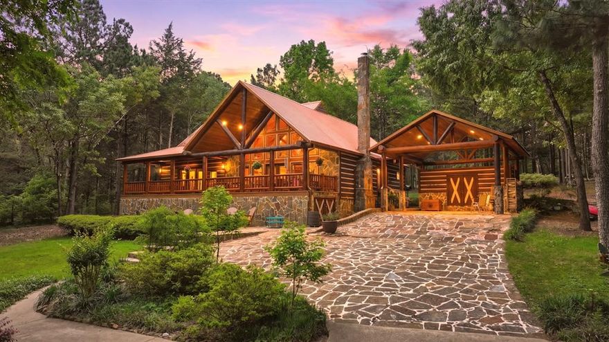 “Location, location, location.” Set within one of the area’s most desirable and established corridors along FM 2137, this property is a place where serene, picturesque surroundings, lush, tranquil landscape, and the gentle presence of an ever-flowing freshwater stream, come together to create something truly special.  
The land itself feels like a private sanctuary. Ten and a half wooded acres create a peaceful, secluded haven where wildlife roams freely and nature flourishes, offering a setting that is both tranquil and breathtaking in every season.
Crafted entirely of wood with no sheetrock, this exquisite, beautifully crafted log home exudes authentic lodge-style character, rich with warmth and texture. Spanning approximately 3,300+ square feet, the home blends timeless rustic charm with modern livability—equally suited for a full-time residence or a restorative weekend getaway.
Inside, soaring vaulted ceilings and a wood-burning fireplace anchor the heart of the home, creating an inviting and intimate atmosphere. Seven fire features—including interior fireplace, fireboxes, and an outdoor grill—offer cozy gathering spaces throughout, enhancing both quiet evenings and memorable entertaining.
Expansive covered porches and open-air seating areas are thoughtfully positioned to embrace the surrounding landscape, inviting you to slow down and take in the sights and sounds of nature. The kitchen is well-appointed with granite countertops, stainless steel appliances, and abundant cabinetry, while the primary suite provides a spacious and private retreat. Additional bedrooms, flexible living spaces, and ample storage ensure comfort and functionality throughout.
With deeded paved road access, the property remains easily accessible while preserving its sense of peaceful seclusion. Select lodge-style furnishings are negotiable, offering the potential for a seamless, turnkey transition.
This isn’t just a house…it’s an experience.