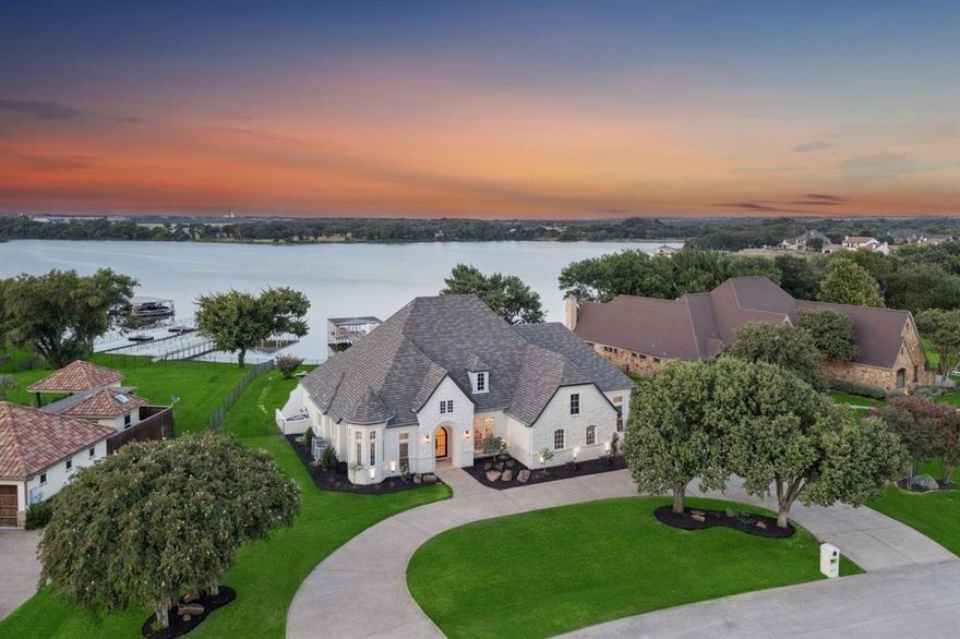 Every detail has been thoughtfully considered in this stunning down-to-the-studs renovation of a premier 5-bedroom, 5-bathroom waterfront estate, located within the prestigious 24-hour gated and guarded community of The Resort on Eagle Mountain Lake. Set on a generous 0.652-acre lot with 92 feet of prime main-body lake frontage, this exquisite home offers the pinnacle of luxury and the ultimate lakefront lifestyle. through a custom-crafted luxury iron front door into an open-concept design anchored by a chef’s kitchen outfitted with professional-grade Thermador appliances, including a built-in refrigerator, double ovens, walk in pantry, and commercial grade range. Custom accordion doors seamlessly connect the living spaces to a brand-new resort-style pool and spa while framing panoramic views of the lake. All but one bedroom are located on the first floor, including a private primary suite with sitting area and spa-inspired bath featuring a walk-in rain shower and custom closet. Upstairs, a bedroom with private balcony and full bath overlooking the lake creates an ideal retreat for guests or family. A mother-in-law suite with separate entrance, living area, kitchenette, and full bath further enhances flexibility for multi-generational living. Additional highlights include a bonus room that could be used as a media or game room, single-story dock with boat lift, hardwood decking, and metal roof. Located in a no wake portion of a cove which creates the most peaceful and serene setting. Residents also enjoy access to the community amenities, featuring an 18-hole golf course, clubhouse restaurant and bar, fitness center, two pools, pickleball and basketball courts and more. This property is a rare opportunity to own a completely re-imagined waterfront estate with world-class finishes, unmatched views, and the resort lifestyle to match.