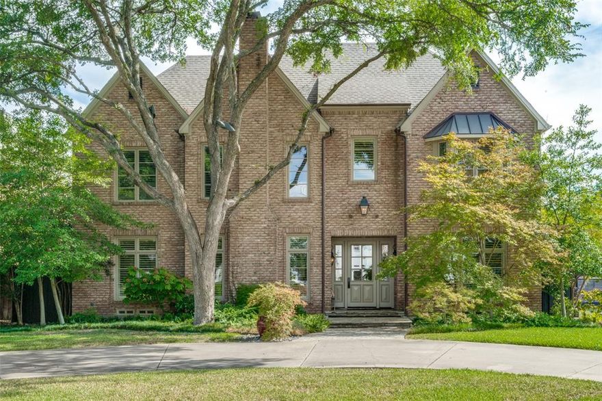 A street with cascading live oaks welcomes you to a brick traditional home with circular drive on a prestigious block of Caruth Blvd. This one owner home enjoys a versatile open floor plan for entertaining designed with great attention to detail. All hardwoods down, the living & dining rooms flank an oversized entry with tall ceilings & windows leading to fabulous family room with fireplace overlooking outside entertaining with stone covered patio, fireplace, grill, and lush landscaping with turfed yard. The family room opens to a cook’s kitchen with island, breakfast room & butler’s pantry. A grand primary bedroom suite with his-and-hers baths & a secondary bedroom with bath (could be a study) are on the first floor with 2 large bedrooms with baths up. Upstairs, the versatile floor plan provides for a playroom or fifth bedroom plus a 'bonus room'. Off attached two-car garage is a mud room & large utility room. New roof Oct 2024. Stellar location is close to NorthPark, Downtown & SMU.