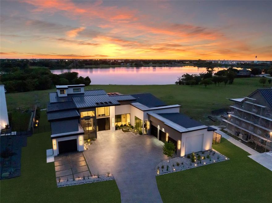 This extraordinary lakefront estate sits on a quiet street of just 13 custom homes in Frisco’s most private gated community. Perfectly positioned on Lake Lewisville, it offers unobstructed water views preserved by protected land, ensuring your sunsets stay breathtaking. Inside, architectural sophistication meets cutting-edge technology, from carbon-steel panoramic doors to a fully integrated smart home system. A dramatic pivot steel front door opens to soaring ceilings, custom steel-and-wood staircase, and a living room with a ventless gas fireplace and 180-bottle wine wall, seamlessly flowing through pocket glass doors to the resort-style backyard. The chef’s kitchen features Sub-Zero and Wolf appliances, a 60” dual fuel range with dual griddles, waterfall quartz island, built-in coffee system, and butler’s pantry. The adjacent bar offers a Sub-Zero wine fridge, Scotsman ice maker, and floating LED lit shelves. The primary suite with accordion doors opens to the backyard paradise and connects directly to a fitness center and a covered yoga patio. Tom Ford inspired closets and a spa bath with steam shower, outdoor shower, and smart features complete the retreat. Additional highlights include a downstairs guest suite with patio lake views, a glass-walled executive office overlooking the 4-car showcase garage that is ideal for car collectors, secure safe room, game room with wet bar, home theater, and three ensuite bedrooms upstairs with balcony access. A huge motor court leads to five indoor parking spaces, including a four car garage with epoxy floors, EV charging, and a car wash detail station and a single car garage with a dog wash station. Outdoors, enjoy a Claffey Pools oasis with a luxury pool with spa, Wolf outdoor kitchen, a gas fire bowl, and travertine decking. With Sonos audio, security cameras, blackout shades, and whole-home water filtration, this home is the ultimate blend of elegance, innovation, and lakeside living.