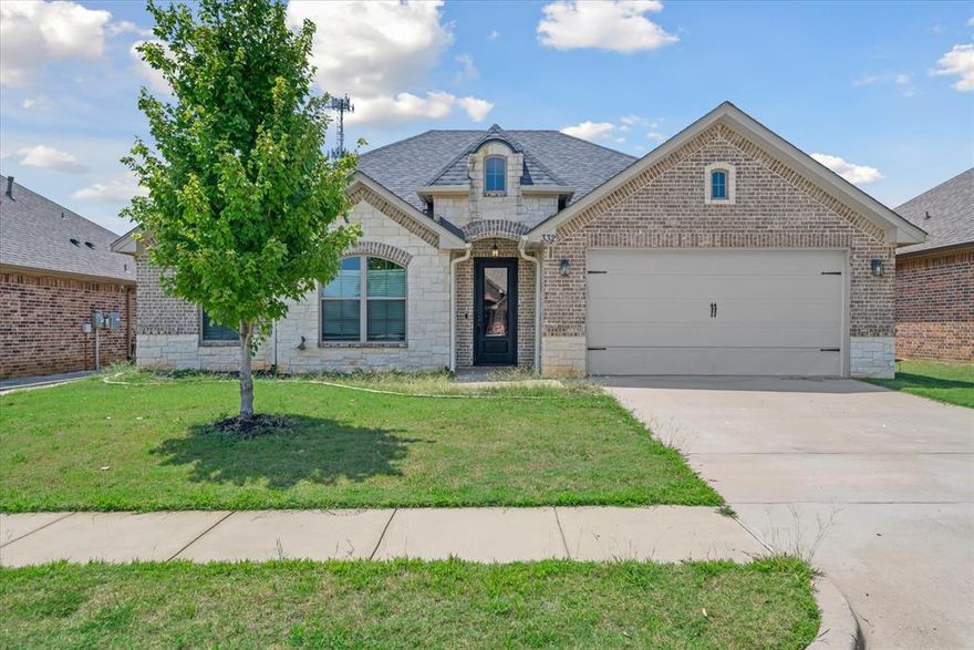 Situated in the sought-after Kingdom Estates neighborhood within Lindale ISD, this home blends comfort, style, and convenience. The inviting open-concept design connects the living room, dining area, and kitchen, creating an ideal space for everyday living and entertaining. The kitchen features granite countertops, custom cabinetry, and a central island with extra seating—perfect for gathering with friends and family. The split-bedroom layout offers privacy, with two rooms and a full bath on one side, and a spacious owner’s suite with a walk-in closet and private bath. Step outside to enjoy a covered patio, a fully fenced backyard, and a full sprinkler system for easy upkeep. Residents also enjoy community amenities, including a 7-acre green space, sidewalks, and streetlights for a welcoming neighborhood feel.