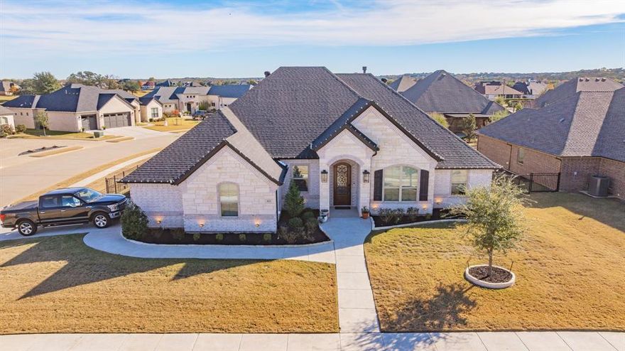 Beautifully designed single-story home located in the gated Harbor Lakes Plantation community of Granbury. This 4-bedroom, 3-bath residence offers 2,591 sq ft of thoughtfully planned living space with high ceilings, quality finishes, and a split-bedroom layout ideal for privacy and functionality.

The open-concept living area is anchored by a striking floor-to-ceiling stone fireplace with a custom wood mantel and flows seamlessly into the kitchen. The kitchen features an oversized island, granite countertops, under-cabinet lighting, walk-in pantry, vent hood, and upgraded 5-burner gas cooktop, making it perfect for everyday living and entertaining alike.

The primary suite is a true retreat with dual vanities, garden tub, extended walk-in shower, linen storage, and a spacious walk-in closet. A private guest suite with en-suite bath, dedicated office with French doors, and additional split bedrooms provide flexibility for work, guests, or multigenerational living.

Additional highlights include a separate utility room with built-in cabinets and sink, epoxy-coated two-car garage, covered patio, sprinkler system, and landscaped backyard. Energy-efficient construction adds long-term value and comfort.

Move-in ready and ideally located near Harbor Lakes amenities, shopping, dining, and Granbury Lake—this home delivers style, comfort, and functionality in one exceptional package.