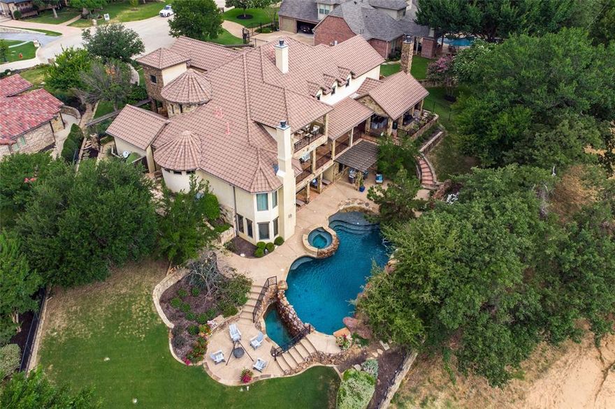 One of a kind tucked away beauty in Colleyville. This gorgeous 7058 sqft Tuscan home has 3 levels of balconies and patios offering the ultimate in privacy & seclusion.  The home has been updated throughout from the teracotta tile patio & outside kitchen to the stand-alone tub and walk-through master shower. Recent interior paint showcases the fabulous beamed ceilings, floor-to-ceiling stone fireplaces & alder wood cabinetry.  The 1371 sqft basement level offers a bedroom with ensuite bath, living area with stone fireplace, media room and pool bath with walk out access to the sparkling custom Hart pool with waterfalls, sun deck & spa. The exterior of the home and backyard is a work of art with the tiered levels just begging for entertaining…plenty of lounge & dining areas plus a fire pit with Adirondack chairs.  Welcome to your own private resort!