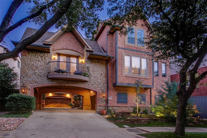 Nestled beneath mature oaks in one of Dallas’s most walkable pockets, this residence feels like a quiet retreat wrapped in the energy of Turtle Creek in SoHiP Neighborhood. Its stone-and-brick exterior, lantern lighting, and wrought-iron details set a timeless, welcoming tone that continues inside. Through the gated entry, a light-filled foyer opens to French doors leading to a private courtyard garden—lush with ferns, soft groundcover, and sculptural trees that create a rare moment of calm in the city. On the main living level, natural light moves across crisp millwork and dark hardwoods. The living room centers around a modern fireplace and transitions easily into a serene dining room shaped by warm neutrals and soft lighting. Arched openings and paneled details add texture and depth, giving every space a thoughtful sense of rhythm. The kitchen blends beauty and function with custom cabinetry, stone counters, mosaic tile, premium appliances, and a fully integrated butler’s pantry. Framed openings keep it visually connected, allowing light and conversation to move naturally throughout the home. Upstairs, the primary suite offers a true sense of retreat with vaulted ceilings, a wall of windows, and a generous sitting area. The adjoining bath features layered stonework, a freestanding tub, dual vanities, towel warmer, and a walk-in shower—crafted for restorative daily rituals. A nearby third bedroom perfect for an office provides dedicated space for work or creativity. A private first-floor guest suite adds flexibility and comfort for visitors or multigenerational living—an elevated alternative to the typical townhome layout, and an easy plan to add elevator. Throughout the home, thoughtful updates and careful maintenance reflect years of intentional stewardship. Just moments from Turtle Creek Park, the Katy Trail, cafés, and Oak Lawn’s dining and cultural scene, this residence blends architecture, comfort, and lifestyle into one beautifully considered experience.