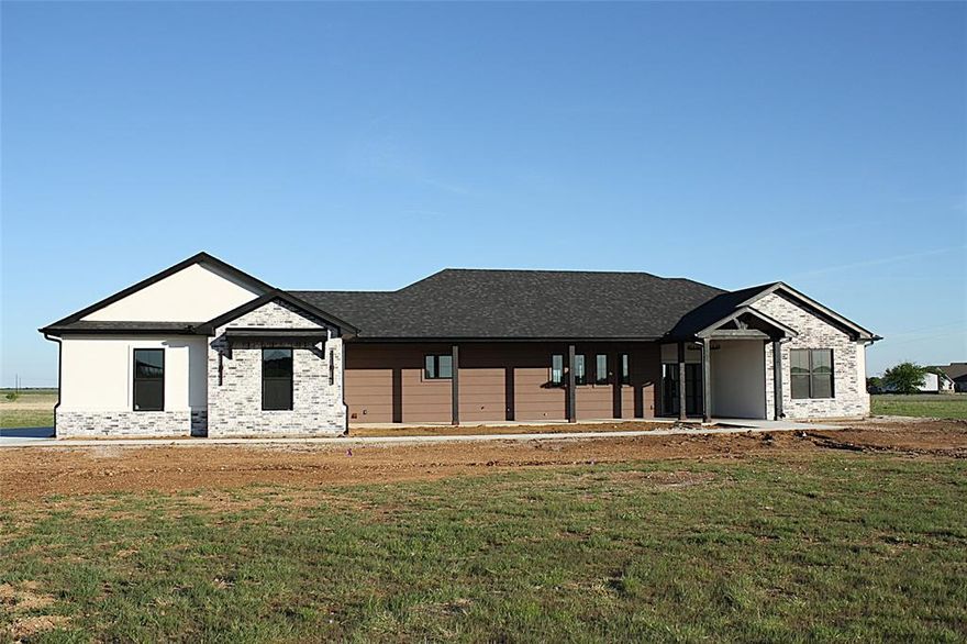 This stunning 4-bedroom, 3.5-bath, 3-car garage home with 2,602 sq ft offers a thoughtfully designed split floor plan and sits on 6.581 peaceful acres in the desirable Willow Moon Ranch subdivision. This property showcases exceptional craftsmanship, energy efficiency, and modern style. Energy efficiency begins with spray foam insulation, making the home extremely efficient year-round. The interior features quartz countertops, custom wood cabinetry, stainless steel appliances including a refrigerator, luxury vinyl plank flooring, ceiling fans in all bedrooms and the living room, and 30-year dimensional shingles. The home also includes a sprinkler system and front and backyard sod. The spacious living and dining area features a stunning beamed cathedral ceiling, abundant natural light, and a multifunction electric fireplace accented with beautiful wood details. The dream kitchen offers generous quartz counter space, double ovens, an abundance of custom cabinetry, a large island, and a breakfast bar with convenient pop-up electrical outlets. Additional highlights include an extra-large pantry with additional storage and workspace, plus a coffee bar with wine cooler. The expansive primary suite features dual vanities, a dedicated make-up nook, a massive walk-in closet, a freestanding soaking tub, and a beautiful tiled walk-in shower. The well-designed laundry room includes custom wood cabinetry, a sink, coat hooks, shoe storage, and quartz countertops for added convenience. One guest bedroom includes a private ensuite bathroom, while the other two bedrooms share a Jack-and-Jill bath, and all bedrooms feature walk-in closets. The oversized three-car garage offers additional storage space. Outdoor living is just as impressive, featuring a large, covered patio with a beautiful wood-burning fireplace and large, covered kitchen complete with a sink. The expansive acreage provides endless possibilities for family recreation, relaxation, and enjoying country living.