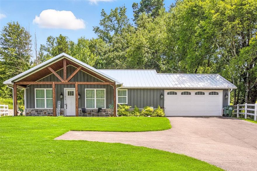 Open-concept barndominium on 4.89 acres. Single-story 2BR + 2BA home with attached 2-car garage, and 1,200 SF interior.Located in Star Mountain Ranch with paved roads, utilities, and community amenities. Open-concept living room, dining area, and kitchen with stainless steel appliances, granite counters, tile backsplash, crown molding, recessed lighting, and ceiling fans. Primary suite includes a walk-in closet, double vanity bath, and direct access to the rear deck. Additional features include pantry, laundry room, high-speed internet availability, central electric HVAC, and security system. Exterior offers a metal roof, metal siding, slab foundation, covered front porch with timber columns, open back deck, fenced yard section with fire pit and swing, and automatic gated concrete drive. The back section of the property is level and suitable for erecting a barn, workshop or office having direct access to Hwy 757. includes a mix of pasture and mature trees with private homesite set back from road. Community anchors include Interstate access within 3–6 miles, UT Health North Campus Tyler- 6 miles, Stillwater RV Resort nearby, Winona Coffee - 0.5 miles, and Winona ISD - 0.8 miles.