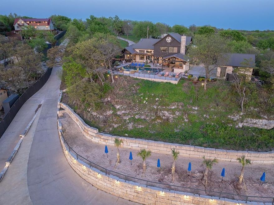 Selling FURNISHED! Magnificent lakeside sanctuary, a luxurious retreat meticulously crafted for entertaining and creating unforgettable memories with family and friends with over 200' of lakefront property!This remarkable residence boasts four spacious bedrooms and four elegantly designed bathrooms,showcasing a wealth of high-end upgrades and features throughout,including custom cabinetry and stunning quartz countertops.Step into the chef-inspired kitchen,where culinary dreams come to life. Outfitted with premium stainless steel appliances,including double ovens and generous storage solutions, this kitchen seamlessly connects to the inviting living area.Here,a grand Austin stone fireplace serves as a breathtaking focal point, while expansive windows provide panoramic views of the serene lake and enchanting sunsets.The primary suite offers a tranquil escape,thoughtfully positioned behind the living space,featuring captivating vistas and direct access to the back porch.Indulge in the sophisticated primary bathroom, complete with dual vanities, a luxurious freestanding soaking tub,and a spacious walk-in shower.Across from the primary suite, the home office with elegant built-ins ensures a productive workspace, while a guest suite adjacent to the kitchen provides comfort for visitors.Venture upstairs to discover a sprawling second living area, game room,and two additional bedrooms,accompanied by a stylish shared bathroom that maintains the home's elegant aesthetic.Outdoors,this property transforms into an entertainer's paradise with enchanting custom lighting,a Zen-inspired pool featuring a sundeck, spa, a cozy firepit,and a built-in grill and bar that overlooks the picturesque lake.A private beach area invites relaxation and fun,while two well-equipped docks cater to all your aquatic adventures.With breathtaking views and deep waters,this luxurious lake house offers the perfect setting to savor the joys of lake life.Don't miss your opportunity to live in lake luxury!