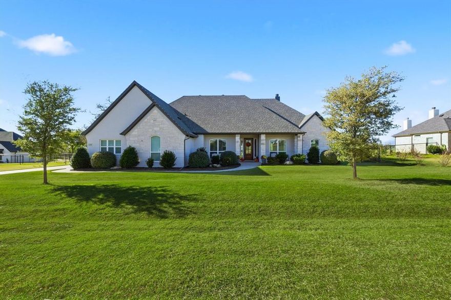Springtown 4 bed, 2.1 bath showstopper on a huge 1 acre lot with a 3 car garage. The mature trees and welcoming front porch set the tone as you arrive. Inside, the home shows like a model with light, neutral finishes and upgrades throughout including handscraped hardwoods in the main areas, plantation shutters, motorized shades, designer lighting and cabinet hardware. A study sits off the foyer with a shiplap ceiling detail. The open concept living room features a vaulted ceiling with wood beams, a stone and brick wood burning fireplace and large picture windows looking out to the backyard. The gorgeous white kitchen includes stainless appliances, double ovens, granite countertops, cabinets extending to the ceiling with glass detail and a walk in pantry. The primary suite sits on the left wing of the home and features wood beam ceiling accents, a walk in shower, separate tub and dual sink vanity. Also on this side of the home is a half bath for guests and a large laundry room. The right wing includes three secondary bedrooms and a full guest bath. Out back, a covered patio overlooks the fenced, cleared and graded acre providing endless possibilities. Additional features include a new 2023 roof and gutters, fiber internet and custom exterior Christmas lights. Ready to enjoy that small town feel with a beautiful custom home?