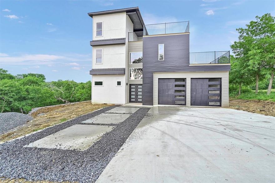 Experience elevated lake living in this brand-new, three-story modern home with breathtaking lake views from the second- and third-floor terraces. Featuring 5 bedrooms and 5 baths, this thoughtfully designed residence offers the perfect blend of luxury, functionality, and flexibility. One of the bedrooms easily doubles as a home office, guest suite, or creative studio—ideal for today’s versatile lifestyle. Step inside and be greeted by clean lines, contemporary finishes, and striking architectural details, including a dramatic open staircase that serves as the home’s centerpiece. Enjoy soaring 12-foot ceilings on the main level and 10-foot ceilings on the upper floors, creating an airy, open atmosphere throughout.
The open-concept layout flows seamlessly into a chef-inspired kitchen complete with a massive center island, solid slab backsplash, professional-grade range, ss appliances, and abundant cabinetry with built-in island storage. Elegant laminate wood flooring adds warmth and sophistication across all levels. Walls of oversized windows bathe the interiors in natural light while framing tranquil views of surrounding nature. Step outside to over 1,700 sq. ft. of outdoor living space across two expansive rooftop patios—perfect for morning coffee, sunset dining, or entertaining under the stars.
Set on a generous 0.31-acre lot backing to Corps of Engineers land, you’ll enjoy exceptional privacy with no rear neighbors. There’s also potential to add a shop, guest house, or detached garage (subject to county approval). The extended tandem garage accommodates up to three cars and features two oversized 10x10 doors—a rare and valuable feature for lake living.
Ideally located near Highport Marina, Tanglewood Golf Course, and a short drive from local casinos and dining, this home delivers it all: location, luxury, lifestyle, and limitless potential. Whether you’re seeking a primary residence, weekend retreat, or investment opportunity, this lake-view gem is a must-see.