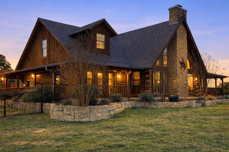 Rustic Elegance Meets Resort Living: Unobstructed sunrise swims, starry nights, and six acres of Texas serenity set the tone for delight at this Hill Country retreat ~ a southwestern escape with a touch of class.

Let this light-filled log home invite you to slow down and savor the setting from a full wraparound porch. Caution: the pool area is a scene-stealer. A peach-hued dawn stretches across a 380-acre private ranch, most days. Imagine afternoons spent poolside, cooling off in the diving pool or soaking in the spa, followed by a sunset dinner al fresco where the laughter lingers. Gather under the stars near an outdoor fireplace, the perfect setting to recap the day’s fishing or boating adventures on the lake.

An inviting gourmet kitchen showcases bright granite counters, a farmhouse sink, and a central island with a gas cooktop. Pull up a bar stool, pour a favorite vintage from the wine bar in the hall, and stay effortlessly connected to conversations unfolding in the great room around the stone fireplace.

Discover a walk-out primary suite on the main level, making it effortless to enjoy fresh air or wildlife sightings. This sanctuary is complete with a jetted tub, custom dual-spray shower, separate closets, and two copper basins with new waterfall faucets. A flexible office offers space to work or create, while the upstairs loft provides for a game room, home gym or guest retreat. Both upstairs bedrooms each offer private ensuite baths, WIC and sweeping views.

Set within a gated community, residents enjoy access to a clubhouse, fitness center, infinity pool, boat ramp, day dock, dry boat storage, and fishing pond. This turnkey property serves beautifully as a full-time residence or weekend retreat. It includes a three-stall garage, enclosed dog run, and AC workshop. Recent updates include a 1yr old roof, outdoor grill, iron fence enclosure, copper sinks, faucets, thermostats, AC coil, pumps and motors. Ask about horse and barn options, if desired.