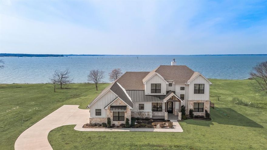Perfectly positioned on the shores of Richland Chambers Lake, this inviting waterfront home is designed for easy lake living and peaceful water views. Tucked away on a quiet peninsula, the property offers 119 ft of shoreline with a steel retaining wall and water steps already in place—ideal for relaxing by the water and ready for a future boathouse. The exterior showcases a fresh modern farmhouse aesthetic, complemented by a 3-car garage offering ample space for vehicles, lake toys, and everyday lake essentials.

Inside, 3,402 sq ft of thoughtfully designed living space includes four bedrooms and four bathrooms. Hardwood floors extend through the main living areas, while the open layout is filled with natural light. The kitchen blends style and function with white shaker cabinetry, quartz countertops, farmhouse sink, subway tile backsplash, and a large island ideal for casual meals or entertaining. It flows into the dining area, where expansive windows and a statement chandelier set the stage for everyday dining or special occasions.

The living room is a focal point, featuring a stone fireplace and walls of windows framing tranquil lake views. Step outside to the patio and attached sunroom—perfect for morning coffee, evening relaxation, or year-round enjoyment. Upstairs, two generous family or game rooms provide flexible space for movie nights, hobbies, or guest accommodations. A discreet storage area beneath the staircase keeps the home organized. Both refrigerators, plus the washer and dryer, are included so you can move in and enjoy lake life immediately.

For added convenience, the home includes a lake pump and whole-home water filtration system. A fenced dog yard with sleek black metal fencing provides a secure, unobtrusive space for pets while complementing the modern farmhouse design.

With high-end finishes, flexible living space, and a prime waterfront setting, this home is ideal for full-time living or a weekend retreat on Richland Chambers Lake.