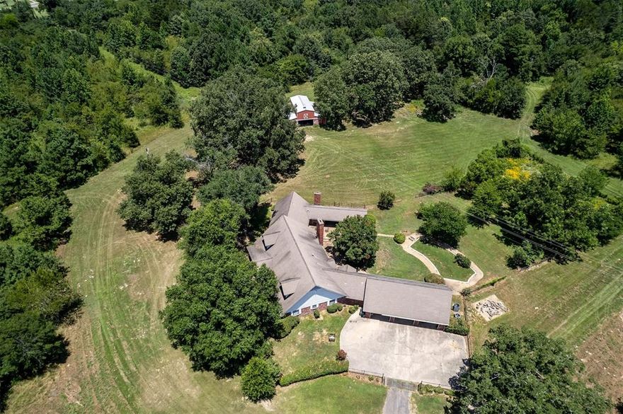 Imagine a home on 40 beautiful acres only 5 minutes from the grocery store. This is a rare find so close to town! Follow the driveway as it disappears among the trees, passes by the lake, and up towards the 3330sf custom built home. The AC was replaced approximately three years ago, and the house was replumbed with pex plumbing. Two major systems updated! A beautiful mixture of trees and cleared land makes you feel like your miles out in the country when you're so close to town! The acreage includes a scenic lake with picnic area; a large barn with stalls, tack room and shop with AC. The property has access from Inwood and FM 1254. The home boasts very large bedrooms with lots of built ins and storage throughout. The two downstairs bedrooms are split from the expansive master with two more oversized bedrooms upstairs. The master is almost 400sf and has an adjoining sewing room which would make a great nursery, office or additional closet. There's a patio kitchen with a fireplace that can be used closed in or open to the back patio. The patio kitchen is on the same side of the house as the master suite...perhaps it's possible to create a mother-in-law apartment from the existing amenities. The laundry room includes a full bath so you can shower off after coming indoors. There's a well and pump on the property allowing you to water your garden and land without a costly water bill. There are two attics - one with walk in access from the second floor of the house and another over the garage. Expensive upgrades in AC and plumbing allows a new buyer to focus on making the aesthetics their own. Appraised for $1.2 million in Aug 2023