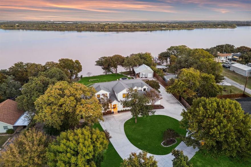 Rare opportunity to own a gated waterfront estate on Eagle Mountain Lake with over a 150 ft. of unobstructed lakefront views. Enjoy unforgettable sunrises and breathtaking water views from every room of this modern lake house, nestled among mature trees on over an acre just 1 hour from Dallas & 45 minutes from Fort Worth. Arrive through a gated entry & circular drive to soaring ceilings, designer finishes throughout, and floor-to-ceiling windows that frame the lake at every turn. The chef's kitchen features Thermador appliances, Jenn-Air commercial induction range, warming drawer, nugget ice maker, & butler's pantry with wine fridge, dishwasher, & sink. The first-floor primary suite is a true retreat — luxurious ensuite with soaking tub, oversized shower, & walk-in closets, all with serene lake views. Upstairs: a spacious living area, three bedrooms — one with a private ensuite & two with a Jack-and-Jill bath — plus an oversized balcony overlooking the water. The guest house offers one bedroom, full kitchen, living & dining area, attached garage, & private deck with lake views. Step outside to a resort-style backyard — sparkling pool & spa, expansive covered patio perfect for outdoor dining & entertaining, & fire pit. Your private dock features both boat & jet ski lifts with direct open-water access. Smart home thermostats & locks, new HVAC, pool & spa heater, tankless water heater & more — full upgrade list available. This exceptional property is unrivaled when it comes to updates, finish out and overall lakefront functionality. and beauty.  No HOA. Don't miss your chance to own this one-of-a-kind waterfront retreat.