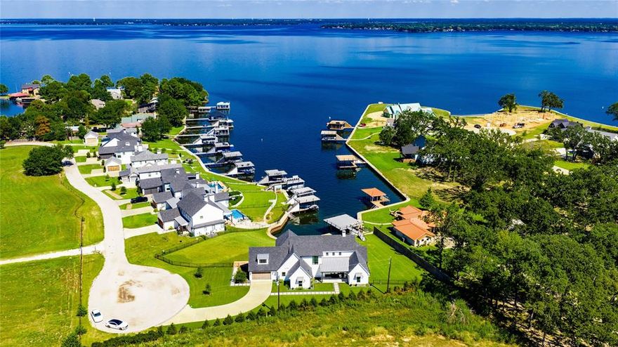 Sprawling modern farmhouse, custom-built in 2022, positioned on two waterfront lots.  Open living and dining with vaulted ceilings, wood floors, and a wall of windows framing stunning lake views.  The cook's kitchen offers an island eating bar, abundant counter space, gas cooking, beverage refrigerator, ice maker, and a butlers pantry. The primary suite features lake views, luxury bath, and a walk in shower.  Three guest en-suites are located on the main level, while the second-level flex room with full bath is perfect for kids or guests.  Outdoor living shines with a spacious covered patio featuring wood ceilings, ceiling fans, fireplace and television.  The large fenced yard leads to a double boathouse with sundeck - ideal for enjoying all the lake has to offer.