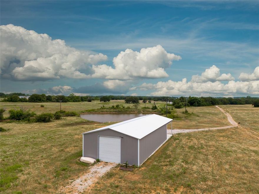 Enjoy your country escape from the start! Turn into the property from CR 1480 through the green pipe gate onto approximately 1800' drive built of rock and caliche base. The front tree line shields the view to the barn. You will pass by the 170' deep water well. This 10.756 tract has also been improved with an insulated 30' x 60' barn with 19' x 30' overhang carport. Slab was set with 2' footings in fiber reinforced concrete.The building has 200 AMP service and set for water and future bath use. Build out the interior living as big as you like or use the 450 sf corner the owner imagined. The front and back garage doors provide drive through ability. Brushes has been installed above garage doors.The front door is 10' high and the back is 12'. The very nice existing pond is split with the west neighbor. Property lines have been set with green metal posts with white tips. The pricing includes equipment detailed in documents. There are 2 electric meters, one on well and one on building.
