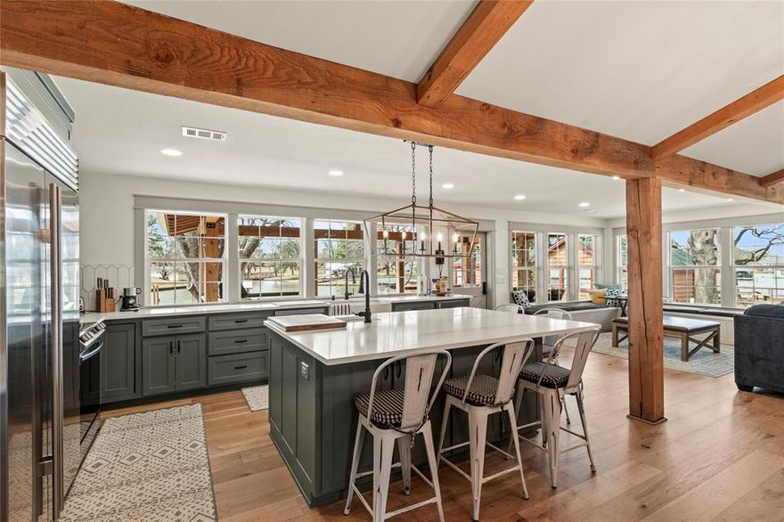 This stunning lake house, fully gutted and expanded in 2023, blends modern farmhouse charm with easy lakefront living. Boasting wood beam vaulted ceilings, shiplap walls, and real wood floors, the open-concept design creates an inviting and spacious atmosphere throughout. The cozy wood-burning fireplace adds a touch of warmth, while the sliding barn doors provide a nod to rustic elegance. With 14 windows across the back of the home, the views are nothing short of spectacular, offering panoramic water vistas from every angle. A corner nook with a window seat creates the perfect spot for family game nights. The gorgeous kitchen is a chef's dream, featuring high-end appliances, including a Sub Zero  refrigerator and freezer, quartz countertops, a beverage refrigerator, and an ice machine. The large island offers plenty of seating and a prep sink, making this space perfect for both entertaining and everyday living. The 550 sq. ft. covered porch overlooks a flat, gently sloping half-acre lot with 125 feet of prime waterfront on a peaceful cove. Enjoy outdoor living by the firepit or under the shade of magnificent magnolia and pecan trees. A circle driveway and ample parking space for multiple vehicles, along with a carport, ensure convenience for guests. A detached 30x24 metal building offers additional parking and storage for vehicles, boat, water toys, golf carts, or could be transformed into a fun waterside game room or workshop. There's plenty of space to add a pool if desired. The new boathouse decking and electric were updated in 2023. Located on the west side of the lake close to Lone Star Marina, Tiki Hut, Figs Steakhouse, Triple N Ranch Winery, and more. Furnishings and watercraft available separately. While the exterior of the home has been beautifully remodeled, you truly have to step inside to appreciate its full beauty.