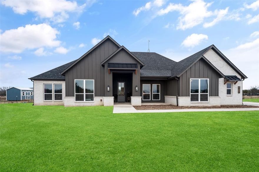 Welcome to this beautifully designed four-bedroom custom home set on expansive acreage just outside of Farmersville, where modern finishes and wide-open views create the perfect retreat. From the moment you arrive, the striking exterior blends board-and-batten siding with brick accents, offering timeless curb appeal and a welcoming front entry.
Inside, the open-concept floor plan is filled with natural light and thoughtfully designed for both everyday living and entertaining. The study is a perfect space for a home office. The spacious living area features a dramatic stone fireplace, soaring ceilings, and large windows that frame serene countryside views. The chef’s kitchen showcases crisp white cabinetry, a generous center island, stainless steel appliances, and elegant pendant lighting, flowing seamlessly into the dining area and living space.
The private primary suite is a true sanctuary, highlighted by a bold accent wall, spa-inspired ensuite bath with dual vanities, a walk-in shower, stand-alone soaking tub, and expansive closet. Additional bedrooms are well-appointed and versatile, ideal for family, guests, or home office needs.
Step outside to enjoy the covered back patio overlooking lush green lawns and rolling acreage—perfect for relaxing evenings, outdoor gatherings, or simply soaking in the quiet beauty of country living. With ample space for recreation, or hobbies, this property offers both comfort and opportunity.
Experience refined rural living with modern style, privacy, and room to breathe—just a short drive from town conveniences.