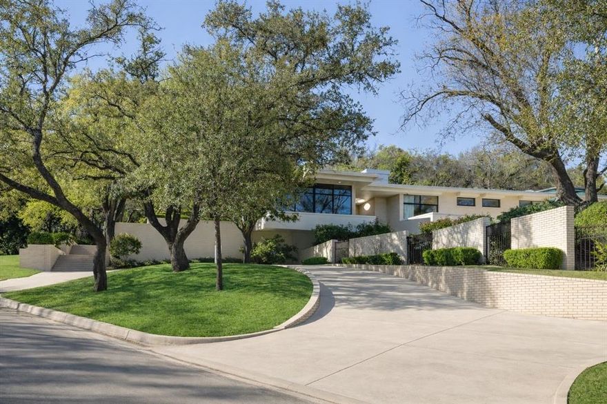 An iconic Westover Hills estate where architectural pedigree and modern indulgence converge.
Originally designed in 1957 by renowned architect Jack Schutts and masterfully expanded by architect
Ames Fender with a striking 5,000+ square foot contemporary addition, this 1.2-acre estate is a private
resort hidden in plain sight. With 5 en-suite bedrooms, 7 full baths, 2 half baths, and garage space for 5
vehicles, the scale is impressive with yet every space feeling intentional. Terrazzo floors guide you
through dramatic entertaining rooms framed by walls of glass. The formal dining room captures tranquil
water views, while the great room anchored by a statement fireplace and bespoke bar opens
seamlessly to a covered terrace crowned with a circular oculus skylight. Indoor and outdoor living blend
effortlessly, creating a setting equally suited for intimate evenings or grand scale gatherings. The chef’s
kitchen is both sculptural and functional, outfitted with professional grade appliances and opening to a
private fountain courtyard. A theatre, executive office, library, and wine cellar complete the interior
experience. The primary suite is its own private wing with a fireplace, library, and sweeping park like
views included offering serenity without sacrificing sophistication. Across the grounds, glass walkways
hover above curated landscaping and water features. The resort-style pool weaves architecturally
between structures, creating a striking visual centerpiece. A 1,000+ square foot air-conditioned cabana
elevates the experience further with a full kitchen, living area, gym, and bath making it perfect for
extended entertaining or private retreat. A rare collaboration between timeless mid-century design and
bold contemporary architecture, this estate is a legacy property designed for distinction, privacy, and
unforgettable entertaining.
