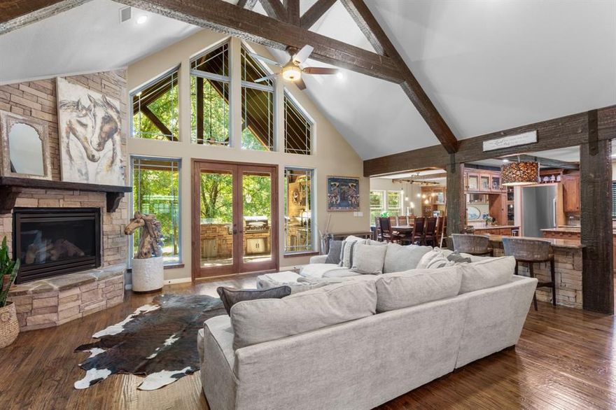 PRICE ADJUSTMENT! Take another look at this luxury ranch style estate is poised on a 1.8 acre lot with many custom upgrades which blend sophisticated craftsmanship with eco-conscious innovation.  Step into a grand open-concept living area, where hand-scraped hardwood floors, LED lighting & soaring ceilings create an atmosphere of timeless refinement. The living area features a corner stone fireplace, tall ceilings with rich wood beams & spectacular views of the patio.  The gourmet kitchen is a chef’s dream, featuring a built in smart refrigerator, a ZLINE gas cooktop, a ZLINE pot filler, & a Bosch dishwasher. The pantry offers an under-counter refrigerator, & custom wood shelving for extraordinary storage. The primary bedroom is on the main level and offers an oversized bathroom with updates and 2 closets. The dressing closet offers special designs for jewelry, accessories and clothing. The basement is an entertainment masterpiece, featuring a custom media center with in-wall surround sound speakers and a subwoofer, a custom library wall, and a custom wine cellar for the collector. There are 2 additional rooms which can be a music room and office. The fourth bedroom offers space for a sitting area and has a built-in desk. A custom patio, centered around a luxurious outdoor kitchen with granite and stone finishes, includes a grill, a refrigerator, sink, and built-in cabinets. The built-in speakers and ambient lighting set the stage for gatherings, while a fire pit adds warmth to serene evenings. The lot is nurtured by a cost-saving well water system with a sprinkler network and dedicated water lines to all the plants, trees and the charming garden, to create a secret oasis.  Sustainability is woven into the estate’s core, with owned solar panels for low electric bills, paired with Smart thermostats and locks on entry doors for seamless control and security. Smart lighting and fan control enhance efficiency across the living room, master bedroom, basement, and attic.