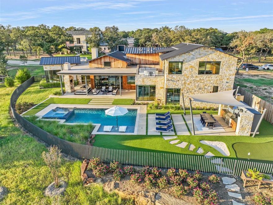 Welcome Home to Modern Luxury Living with a waterfront view!! Peacefully set in coveted Stony Brook, this contemporary gem was thoughtfully built by Holmes Custom Homes and designed to enjoy natural light, exquisite lake views, sophisticated architecture & warm natural elements. Walls of glass frame the serene backyard views, creating a seamless connection between the indoor & outdoor living spaces. The open Living Room impresses with natural light, soaring vaulted ceiling, exposed wood beams, wide-plank wood floors and a sleek modern fireplace with fireballs. The Chef’s Kitchen is both functional and beautiful, featuring stone countertops, custom cabinetry, a dramatic oversized island, designer lighting & large Pantry-Prep area ideal for everyday living and entertaining. Premium appliances include a full-size Sub-Zero refrigerator & freezer, full-size SubZero wine fridge, Wolf range and microwave + Miele dishwasher. The private Primary Suite is a tranquil retreat with beautiful backyard views, boutique style walk-in closet, and spa-bath with soaking tub & gorgeous shower. The versatile floor plan offers 2 additional Bedrooms w en-suite baths on the main level + two additional bedrooms upstairs. The spacious upstairs Game Room is ready with wet bar, flat-screen TV + a balcony to enjoy the lake views. A striking floating staircase with custom built-ins creates a dramatic architectural focal point. Additional highlights: quartz countertops in the Utility room, a Whole-Home Generator & two separate 2 car garages, one equipped with an AC split. Step outside to your private Resort-Style Backyard Retreat boasting a sleek modern Claffey pool and spa, manicured landscaping, Outdoor Kitchen with modern cover, and peaceful views overlooking the neighborhood pond and green space. Residents enjoy tranquil walking paths and access to a community pavilion, creating a lifestyle that perfectly balances luxury, nature, and modern design. **Open Enrollment to Southlake Carroll ISD **