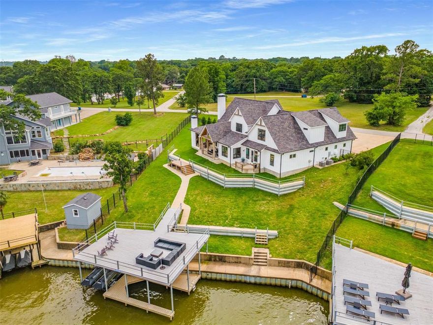 Just one hour from Dallas, 205 Oak Creek Drive isn’t just a lake house—it’s a destination. Perched above the shoreline in the heart of Cedar Creek Lake, this custom modern farmhouse delivers sweeping water views, refined indoor-outdoor living, and spacious design ideal for gathering friends and family year-round. Inside, the open-concept layout centers around a vaulted great room with warm wood beams, shiplap walls, and a stone fireplace. Expansive windows and French doors flood the space with natural light and stunning lake views. The designer kitchen boasts quartz countertops, a large island, and premium finishes—perfect for morning coffee, holiday spreads, or casual dinners for twelve. The flexible layout includes a main-floor study (or guest suite) with a full bath, plus a secluded primary suite with private patio access to enjoy sunrise on the water. Upstairs, two guest bedrooms with en-suite baths provide comfort and privacy, while the massive rec wing includes a bunk nook, full bath, game room, and private bedroom—ideal for kids, teens, or extended guests. Outside, a wraparound covered porch with porch swings, an outdoor fireplace, and built-in grill offers the ultimate entertaining space—perfect for hosting Thanksgiving by the fire or watching football with a lake breeze. The fenced yard leads to a private boathouse with a 25-ft boat slip, two jet ski lifts, and a party deck with open water views. Located in the friendly Arnold Hills community, 205 Oak Creek is perfect as a full-time home, holiday hub, or weekend retreat—just a short drive from the city, but a world away in experience.