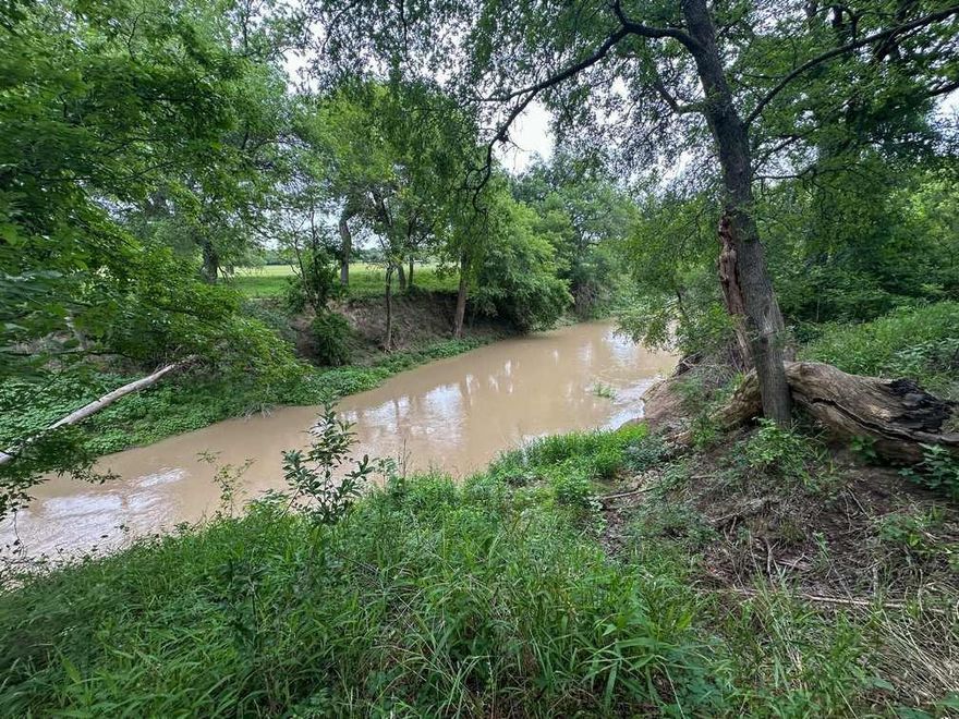 This 32-acre live water property along the Leon River features over 675 feet of year-round frontage, offering fishing, kayaking, and riverside relaxation. The land includes native Texas hardwoods—oak, pecan, elm, and ash—with minimal cedar and sandy loam soils. Rolling topography and established trails make it feel larger than its footprint. A deep water well supports homestead or livestock needs. The owner has found arrowheads, suggesting a historic Native American camp. Wildlife is abundant, with frequent sightings of deer and turkey. A chicken coop houses egg-producing chickens and free-ranging guineas. Improvements include a 1996-model manufactured home, storage buildings, covered porches, and a pump house with washer and dryer hookups and full bathroom. Vivid sunrises over the river and colorful sunsets across the pasture complete this private and well-rounded property.