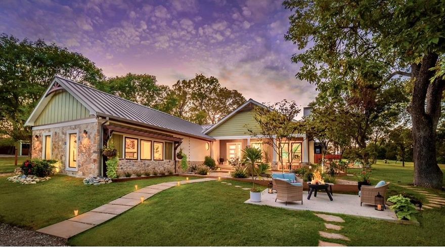 Secluded beyond view and embraced by nature, this remarkable 5+ acre ranch delivers elevated country living with sweeping panoramic views. Designed with refined elegance and wrapped in Santa Barbara Smooth Stucco, the home is perched beside a peaceful pond, offering a setting where luxury meets serenity. Equestrian enthusiasts will love the two-stall horse barn and open grazing pastures coastal Bermuda & winter rye! Room to roam, squirrels to chase — your pups will be in paradise! Crafted for those who appreciate thoughtful design, the home is not merely renovated—it has been reimagined. The great room welcomes you with an ash wrapped ceiling beam, LVP flooring and a WBFP. Expansive windows and an 8’ Pella sliding glass door create a seamless connection to the outdoors, letting nature become part of your everyday living. At the heart of the home, the kitchen impresses with a maple hardwood inlay that defines the ceiling—a detail that adds architectural interest. A 14' quartz island with a waterfall edge anchors the space, ideal for gathering, prepping, and entertaining. Euro-style cabinetry with soft-close drawers, marble accents, and GE Café Matte White appliances—including an induction cooktop and double convection ovens—combine form and function, while a modern beverage station and ambient lighting elevate the overall experience. Wander down a custom-tiled hallway to discover a guest suite worthy of a boutique stay, complete with a walk-in closet and full ensuite bath. Two additional guest rooms—one with a character-rich brick accent wall and another featuring antique reclaimed doors—share a revamped hall bath. The primary suite feels like a private retreat, where walls of glass frame serene views of the creekside setting. A linear fireplace lends warmth & modern elegance, while a custom walk-in closet offers tailored storage. In the spa-inspired ensuite, dual shower heads, exquisite tilework, and double vanities come together to create a daily ritual of luxury.