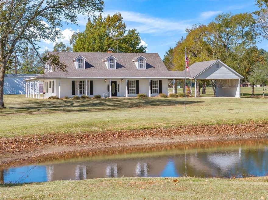 Welcome to your own slice of East Texas charm. An inviting property where peaceful views, thoughtful updates, and endless possibilities come together on beautifully manicured 5 acres. From the moment you step onto the wraparound porch overlooking the serene pond, you’ll feel the warmth and comfort this home provides. It’s the perfect spot to enjoy your morning coffee, unwind at the end of the day, or simply take in the natural beauty around you. Inside, the home blends cozy character with modern upgrades, offering spaces that make everyday living feel special. Recent updates include quartz countertops, dishwasher and microwave, 2 inch blinds throughout, updated bathroom showers and fixtures, kitchen lighting, closet flooring, and an updated electrical panel and panel cover in the workshop  The property features a spacious workshop equipped with Phase 3 electricity and bathroom with an area for office or extra storage. Whether you envision a cabinet shop, welding shop, hobby space, or a place to run your business, the setup offers exceptional flexibility. The circular driveway with front and back access provides easy maneuvering for trailers, equipment, or multiple vehicles ideal for work or play.  This inviting property offers the perfect blend of comfort, functionality, and country living ready to welcome you home.