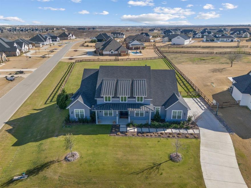 Laid back luxury lives here! 3201 Dovehill Dr. is an inviting retreat designed to feel like a vacation every single day. Built by premier local builder, Noble Classic Homes, this exceptional residence sits on just over an acre in Northlake offering space, privacy, and a true sense of escape. From the moment you enter, high ceilings, wide plank wood floors, plantation shutters, and designer touches set a calm, sophisticated tone. A subtle blue palette woven throughout the home evokes a coastal retreat inspired feel that is both peaceful and polished. The heart of the home is the stunning chef's kitchen anchored by a massive island, ceiling height cabinetry, high end appliances, butlers pantry, walk-in pantry, and bar cabinetry with wine fridge. Designed for both entertaining and everyday enjoyment, the kitchen opens to both the main living and the outdoor living space. Perfect for seamless indoor-outdoor gatherings! The main living room features custom built-ins and a marble tile surround gas fireplace, while large sliding doors open wide to the backyard extending your living space outdoors. A separate family room offers a relaxed hangout, kitchenette area, and backyard access. Private guest quarters are tucked away creating a ideal retreat for visitors. The primary suite is a sanctuary filled with natural light and paired with a show-stopping spa-like bath featuring Carrara marble, pedestal soaking tub, an oversized walk-in shower, large custom closet and storage area. A dedicated office with built-ins provides a charming and quiet place to work. 
Outdoors, unwind year-round with a covered living area, outdoor kitchen, and fireplace. An oversized 3 car garage with epoxy floors completes this thoughtfully designed home where every detail invites you to slow down, entertain effortlessly, and live like you're on vacation every day!  
Enjoy nearby walking trails, local high end dining and shopping with quick access to I-35, all within 20 miles of DFW airport.