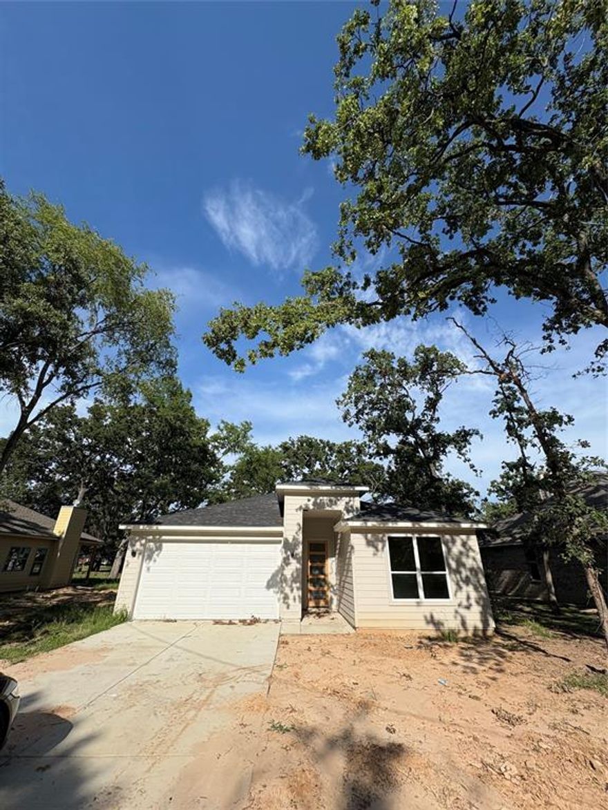 This contemporary - modern 3 bedroom, 2 bath home is designed for both style and convenience. The kitchen features a built-in refrigerator, dishwasher, electric cooktop, oven, and a spacious island, complemented by elegant built-in features and a chandelier. Enjoy cozy evenings by the wood-burning fireplace in the open living area with luxury vinyl plank flooring throughout. The laundry room is equipped with hookups for an electric dryer and washer. Outdoors, you'll find covered parking with a concrete garage. Located in a community with access to golf, a lake, and parks, this home also benefits from city sewer and water utilities. Perfect for modern living with a touch of sophistication!