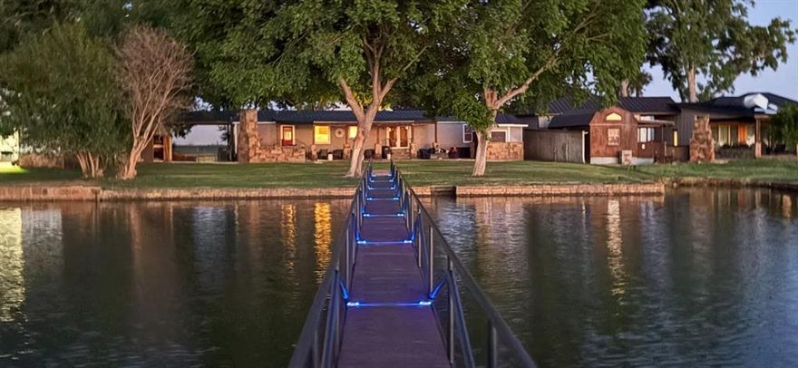 Perfect for pilots. Fly in to Possum Kingdom F-35, and walk just across the street for the most spectacular sunsets on PK. Tree lined circle drive to this Perfect Lake Retreat, designed with family gatherings in mind. Comfortable 3-2 with 1200 sq foot of lakeside outdoor living space complete with outdoor kitchen, handsome stone fireplace, stone outdoor shower, and fully enclosed bar for entertaining and relaxing. Expansive kid friendly play-yard just off the waters edge. Sizable swim dock was painted and re-decked within the last year. Perfect for fishing, sunbathing and relaxing while taking in the gorgeous view.  Upgraded custom rock retaining wall with steps into the water to protect from erosion. Large Carport as well as 2 car garage for all of your lake toys. This property is a fantastic vacation rental with proven income potential, or a perfect full time Lake Residence. New metal roof installed last year.