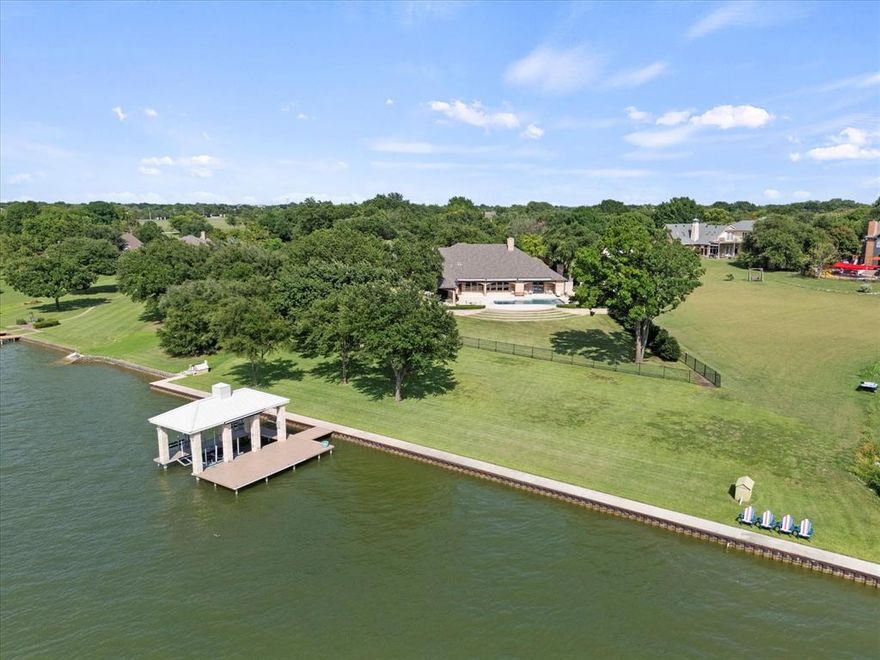 Waterfront estate resting on 1.65 acres with pristine 200 feet of Lake Ray Hubbard shoreline with seawall offering panoramic lake views. Expansive vistas of sunsets and sailboats. Boat house with boat lift and 2 waverunner lifts. Perfect for motorboat or jet skis. Grecian-style pool is surrounded by lush, groomed grounds with seating areas. Outdoor covered living space with fireplace. The grand entry welcomes you with exquisite elegance and versatile design. Large open living and entertainment areas. Sand and finish. Herringbone pattern wood floors. Gourmet chef's kitchen is culinary experience. Separate large Butler's Pantry. Second living area plus a theater room. Primary suite is a true ensuite hosting its own living area with a fireplace, separate entry to the pool and spectacular lake views. Second primary bedroom upstairs. All bedrooms have ensuite bath. Flex room upstairs for multi-uses including a 5th bedroom. Two separate garages, 8 car spaces; 1 garage has workshop and more valuable storage space. Stately gate entrance leads to private drive which presents a country feel but is close to all of the conveniences. HURRY! This jewel box won't last long