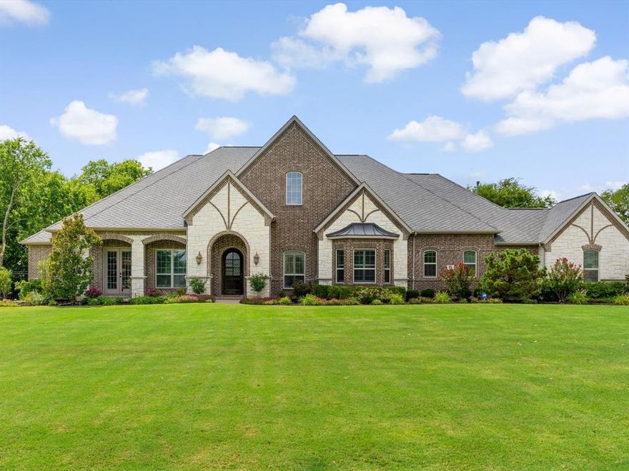 Set on 1.23 acres in desirable Sunnyvale ISD, this single-story Paul Taylor custom home balances luxury with livability. From the moment you enter, you’re greeted by striking barrel ceilings accented with a custom Italian marble design, sparkling glass bead chandeliers, and hand-scraped hardwoods. Wood beams, crown moulding, and plantation shutters carry a sense of sophistication throughout the space. The tree-lined backyard creates a private retreat complete with a pool, outdoor kitchen, fireplace, and travertine decking. The spacious kitchen features granite countertops, stainless steel appliances, a 6-burner gas cooktop with pot filler, double ovens, a huge island, a butler’s pantry with LED cabinet lighting, and a pantry with abundant shelving. The living area boasts a wall of windows overlooking the backyard and a stone fireplace. The private, spacious primary suite offers gorgeous views of the backyard and a gas log fireplace. The en-suite bathroom features a glass bead chandelier, three vanities with Italian marble stain, and a built-in 32-inch MirrorVue TV. The suite also offers a separate soaking tub, a large walk-through shower with dual shower heads, and a custom closet with a built-in dresser, extensive shelving, and its own washer and dryer.The additional bedrooms each include a full bath and walk-in closet. Entertain with ease in the game room featuring built-ins, a wine rack, sink, microwave, and mini fridge. Relax with TV or movies in the separate media room.Additional features include a 4-car garage, iron privacy gate and fencing, motorized solar shades, 1,000-gallon buried propane tank, Starpower home network, and 50 yr architectural shingles, french drains, sprinkler system, and extensive landscaping.