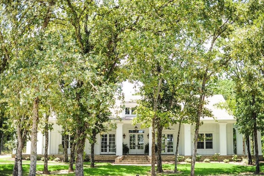 Custom built in 2018 on nearly 5.5 acres of wooded land, this extraordinary estate showcases a level of craftsmanship & design worthy of the pages of Architectural Digest. A long, scenic drive welcomes you to the main residence, where a charming front porch sets the tone for the elegance within. Inside, the expansive living area is designed for both grand entertaining & intimate gatherings, featuring a stunning fireplace, thick moldings, stately columns, high ceilings, & 3 sets of double doors that open onto the front porch. Reclaimed wood floors flow throughout, infusing warmth & character into the home’s refined aesthetic—where Old World charm meets modern luxury in timeless harmony. Two bedrooms share a beautifully appointed Jack&Jill bath. A third bedroom enjoys access to a spacious hall bath distinguished by its curved wood-paneled ceiling & abundant storage. The primary suite offers a serene retreat, highlighted by a cozy reading nook with built-in bench seating & custom shelving. The spa-inspired ensuite bath features a soaking tub, oversized shower & custom sauna—creating a true sanctuary experience. An additional living room with built-in cabinetry offers flexible use as a study, media room, or playroom. The gourmet kitchen is both elegant & functional, offering a large eat-in island, corner breakfast nook, premium appliances, & sink overlooking the tranquil backyard through a wall of windows that bathes the space in natural light. The expansive laundry room doubles as a thoughtfully designed utility space, complete with a dog wash, desk area, & plentiful cabinetry. Off the kitchen, a screened porch provides a peaceful setting to relax & unwind. A detached garage includes a convenient half bath & stairs leading to a private garage apartment above, featuring a fireplace, full bath, & balcony. Completing this exceptional property are a barn with corral, chicken coop, & treehouse—offering a rare opportunity to embrace refined country living without compromise.