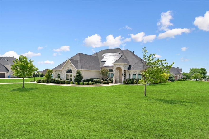 Welcome to this stunning brick and stone estate nestled on 1.4 acres in sought-after Parker Ranch Estates. Offering 5 bedrooms, 4.5 baths, and 4 spacious living areas, this home perfectly blends luxury, functionality, and comfort. Step inside to find beautiful engineered hardwood floors and an elegant tray ceiling in the foyer, setting the tone for the thoughtfully designed interior. The main living area features a striking stone fireplace with gas logs and seamlessly flows into the chef’s kitchen, complete with gray quartz countertops, white shaker cabinetry, dual pantries, a 6-burner gas cooktop, dual Electrolux ovens, pull-out trash, and a dedicated coffee bar. The oversized utility room offers exceptional storage with additional white shaker cabinets, a mud bench, and space for a freezer. Entertain with ease in the media room featuring double doors, a wet bar, mini fridge, and custom cabinetry. The private primary suite is located downstairs and includes a sitting area, plantation shutters, and a luxurious ensuite bath with dual vanities, garden tub, dual shower heads, and direct access to the pool area. A front office provides the perfect work-from-home space. The downstairs layout also includes two secondary bedrooms, each with their own ensuite baths. Upstairs, you’ll find two additional bedrooms and a spacious game room. Step outside to your personal backyard oasis. Designed for both relaxation and entertaining, the resort-style pool features turf surround, a tanning ledge, 12-person spa, swim-up bar, firepit area and a beautiful waterfall. Enjoy evenings under the pergola with space for grilling and a fully equipped outdoor living area with refrigerator and built-in trash. Additional highlights include an oversized driveway, 3-car garage, and strategically planted trees for added privacy around the pool. This exceptional property offers luxury living both inside and out—don’t miss the opportunity to call it home!