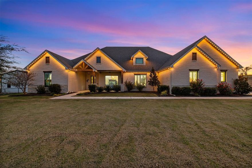 Luxury, land, and lifestyle come together in this stunning single-story custom estate tucked inside the coveted Maravilla Estates of Aledo. Set on two immaculate acres and zoned to top-rated Aledo ISD, this home delivers refined design, thoughtful functionality, and high-end craftsmanship at every turn. From the moment you step inside, elevated finishes set the tone—engineered hardwood floors, statement lighting, and premium cabinetry throughout the main living spaces. The great room is a showstopper, featuring soaring vaulted ceilings with exposed beams and a striking brick fireplace that anchors the space. It flows seamlessly into the chef’s kitchen, where an oversized quartz island, farmhouse sink, double ovens, and extensive storage make entertaining effortless. A generous dining area nearby invites both everyday meals and special gatherings. The primary suite is a true retreat, offering spa-inspired relaxation with custom pecan cabinetry, dual vanities, an oversized rainfall shower, and a soaking tub enhanced with integrated red-light therapy. Three additional bedrooms provide flexibility, including one with a private bath—ideal for guests or multigenerational living. Work and play are equally well-appointed here. A front home office features floor-to-ceiling custom built-ins with quartz surfaces, while a dedicated media room is pre-wired for immersive theater sound. Step outside to the screened, tiled patio—perfect for al fresco dining—then explore the expansive grounds complete with a 30x40 red-iron workshop, a 12x20 storage building, and wide-open space to enjoy. 
The oversized three-car garage includes a climate-controlled bay for hobbies, plus a Tesla charging station for modern convenience. Jellyfish exterior lighting around the entire exterior completes the package. Homes of this caliber, on acreage, in Maravilla Estates are rarely available. Schedule your private tour and experience this exceptional property in person.