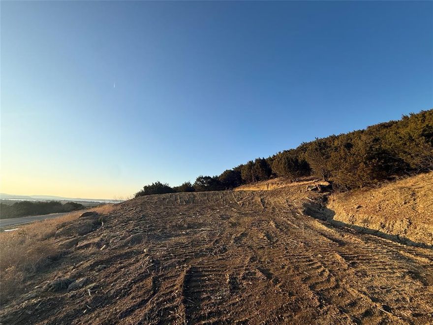 Build your dream home or weekend escape on this serene 2-acre hillside homesite in the sought-after Hills Above Possum Kingdom Lake. Set along a scenic rocky slope, the property offers striking natural character and the potential for elevated views—an ideal canvas for a thoughtfully designed custom home. The homesite has already been leveled, providing a valuable head start on construction.

Located within a private, gated Hill Country community, this property offers a peaceful sense of seclusion surrounded by native trees, natural stone, and wide-open skies. Water and electricity are available at the street, making it easy to bring your vision to life.

Ownership includes access to an impressive array of amenities, including boat storage, a community boat ramp and dock, clubhouse with pool and fitness center, fishing pond, lake access, picnic area with cabin, nature trails, and more than 20 miles of private roads—offering the perfect blend of recreation and relaxation.

There is no timeline to build, allowing you to plan at your own pace and select the builder that best fits your vision. CCRs require a minimum 2,500 sq ft residence. The owners also have thoughtfully designed home plans available that would fit beautifully on this homesite and may be customized if desired.

The adjacent lot is also available, offering the rare opportunity to expand to approximately 4 pristine acres for added privacy, flexibility, or a larger estate setting.

Enjoy the balance of privacy, space, and resort-style lake living—just under two hours from DFW.