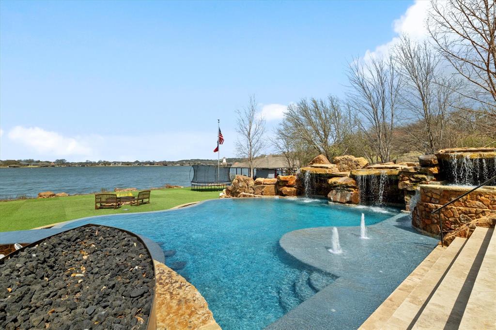 Discover unparalleled elegance in this 8,655 sqft of total living space on Lake Granbury! Boasting 5 beds, 5.1 baths, and a resort-style 80,000-gal saltwater pool, this home offers a swim-up bar, two waterfalls, a spa with a cascading waterfall, and a Paramount self-cleaning system.

Inside, no detail was overlooked! Enjoy all-new designer finishes, custom marble bathrooms, Savant whole-house entertainment, and a state-of-the-art 8-seat home theater with 8K TVs, premium surround sound, and a fully integrated smart system for the ultimate viewing experience.

For those who work from home, the executive office and private library with a fireplace provide a sophisticated retreat. The gourmet kitchen is equipped with top-tier appliances, custom cabinetry, a Miele coffee system, and high-end fixtures.

Step outside to the ultimate backyard oasis! A 2,100 sqft cabana features a full marble bath also plumbed to have a full indoor kitchen in the pool house, while the outdoor kitchen is a chef’s dream with a wood pizza oven, 700-series Southern Pride smoker, BBQ grill, prep fridge, freezer, and stainless wash sink.

Water enthusiasts will love the designated boat dock at the community marina, and the property is approved for a custom-built private dock right in front of the home!

This home is built for comfort and efficiency with a new Brava slate roof (100-year material warranty), new HVAC with a 10-year labor and equipment warranty, copper-infused gutters, and all-new electrical systems, including a 1,000-gallon propane tank with LP gas. Smart home features include Savant automation, LED lighting, ceiling speakers throughout, custom window treatments, smart garage doors, and a fully upgraded security system.

Additional highlights include expanded front and back walkways with elegant Terrazzo tile, new hardwood floors upstairs, custom shutters and drapes, a grand entry chandelier with remote cable controls, and ceiling fans in every room.