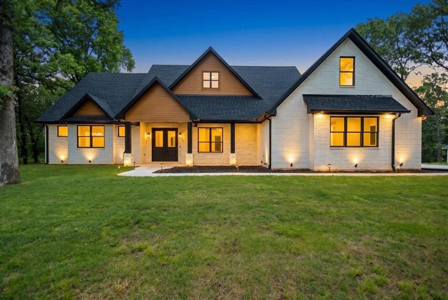 Tucked away in the sought-after Reserve at Tuscany, this exceptional custom home offers a rare blend of luxury craftsmanship and peaceful East Texas living. Surrounded by mature trees and scenic views, the property provides a true sense of retreat. Inside, hand-scraped Red Oak floors, soaring ceilings, and expansive windows create a light-filled, inviting atmosphere. The kitchen is a true showpiece, featuring quartz countertops, a ZLINE 6-burner range, and custom cabinetry with soft-close doors, spice racks, adjustable shelving, and thoughtfully layered accent lighting that elevates the entire space. The privately situated primary suite features a trey ceiling, wall sconces, and a ceiling fan with built-in WiFi. The ensuite bath offers dual sinks, a soaking tub, a spacious walk-in shower, and two walk-in closets, creating a layout that feels both open and beautifully finished. Two secondary bedrooms are connected by a Jack and Jill bath, while the fourth bedroom at the front of the home provides a versatile option for a dedicated office. The utility room is well-equipped with a sink, cabinetry, storage closet, and space for a freezer. Thoughtful details continue throughout, including a stunning built-in display with accent lighting, an expansive pantry, oversized garage, subtle floor lighting, spray foam insulation, 8-foot solid core doors, tankless water heater, high-speed internet, and gas access on the back patio for grilling. The exterior is equally impressive, with beautifully designed lighting and electrical already in place for holiday lights and a future pool. Welcome home, where thoughtful design, quality craftsmanship, and timeless style come together to create something truly special.