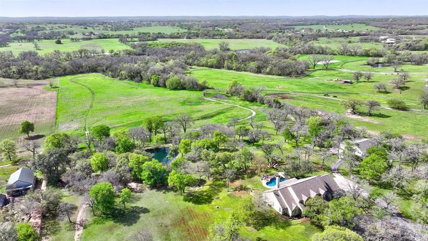 LOCATION! LOCATION! This expansive country estate is situated on nearly 30 acres of land in the Aledo ISD. With its spacious 4 bedroom, 3.5 bath residence spanning over 4300 sqft, two living areas, two dining areas, and a kitchen perfect for entertaining. The outdoor living space offers a view of the sparkling pool and the vast acreage. Additionally, there is a 2600 sqft barn with three stalls, a tack room, and an apartment, providing ample storage space for equipment and hay.The property features beautiful trees, sandy loam soil and coastal Bermuda pastures, making it ideal for horses and cattle. A large aerated pond is located in the center of the property, while a fork of the Trinity river flows at the back. Situated in the heart of horse country, this property is a paradise for outdoor enthusiasts. With its convenient location, only 23 minutes from Will Rogers, close to HEB, and less than 10 min to Parker County Airport, this is truly an exceptional place to call home.