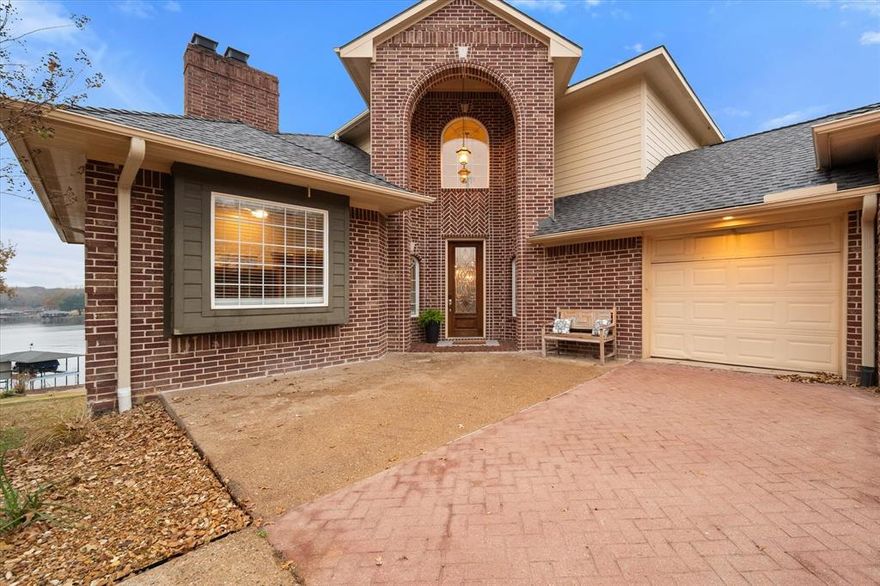 Experience elevated lakefront living in this stunning multilevel retreat designed to maximize panoramic water views and stunning sunsets. Perfectly positioned on the 1.5 acre lot, this exceptional home features a douple decker boatdock with a jet ski lift. Inside the residence offers three spacious bedrooms and two and a half baths, complimented by a versital bonus room that can serve as a 4th bedroom or office. Warmth and character abound with three wood burning fireplaces placed to create inviting gathering spaces throughout the home. The main floor is home to an open concept living room, dining room, and kitchen with breakfast nook. The upper level is solely dedicated to the primary retreat. The oversized primary bedroom and bathroom have incredible lake views both day and night! The lower level is home to a large family room, game room with wet bar and a space for game or dining table. Also located on this floor are the two additional bedrooms, a bath and storage.  French doors lead out to the porch and to the walkway to the lake.  A nice brick patio is located lakeside making it a perfect place for al fresco dining. The owners have completed many updates including 3 new  HVAC units in 2019, a new roof in 2023, and new paint throughout. Whether you're seeking a full-time residence or a weekend escape, this lakefront property offers unmatched views, direct water access and timeless appeal.